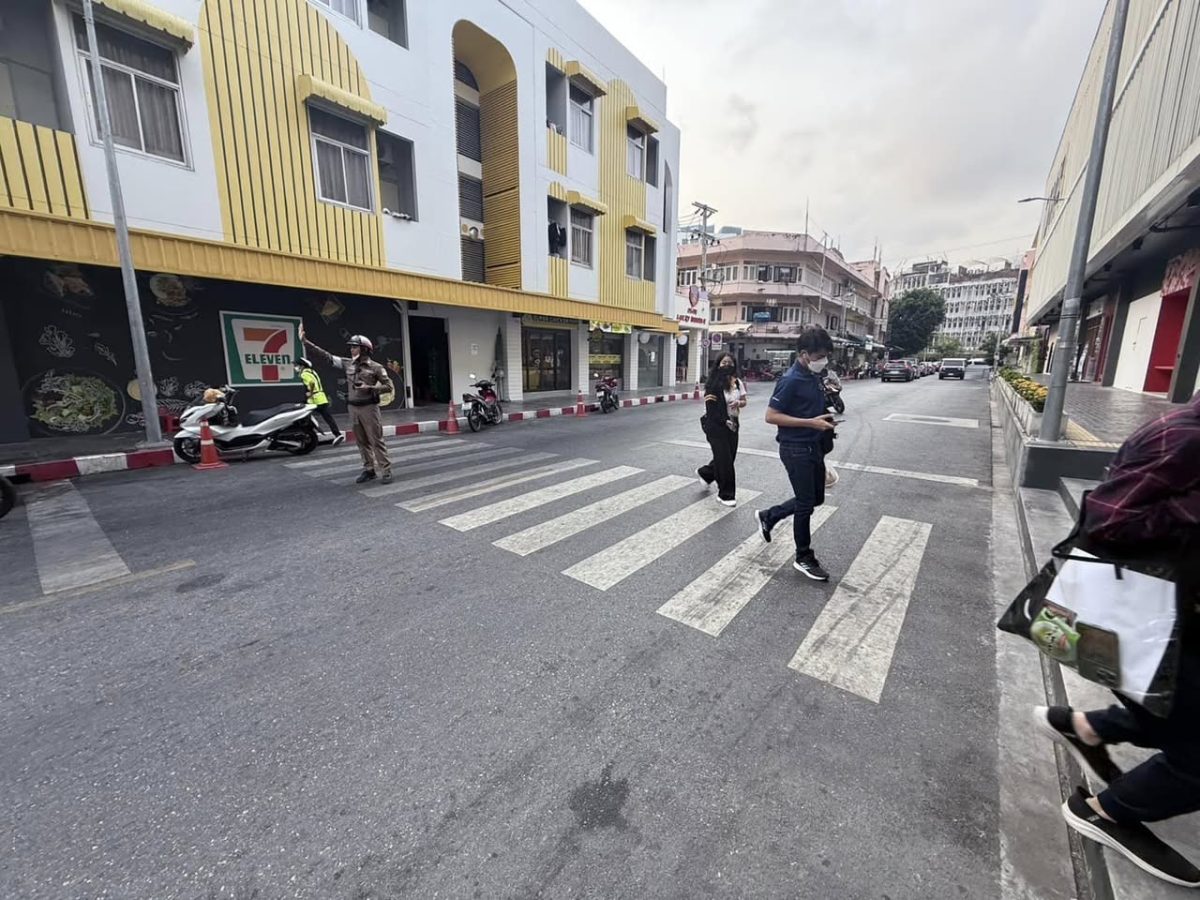 เจ้าหน้าที่ตำรวจจราจร อำนวยคนข้ามทางม้าลายพร้อมรณรงค์ให้ผู้ขับขี่หยุดรถ ให้แก่คนข้ามทางม้าลาย